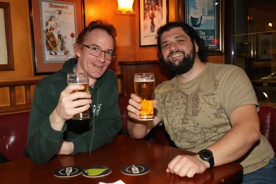 Zwei Gäste stoßen mit Bier an